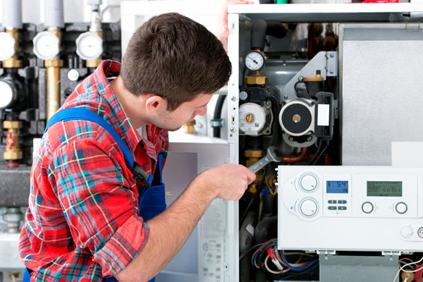 Heating technician repairing boiler controls in West Covina