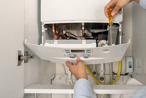 Heating technician repairing a residential boiler in West Covina