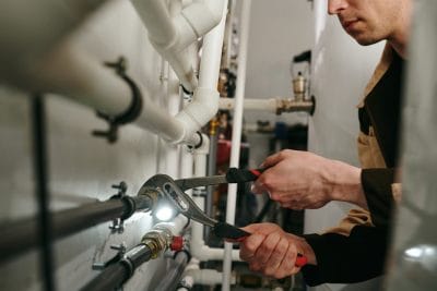 Technician inspecting commercial plumbing pipes in West Covina