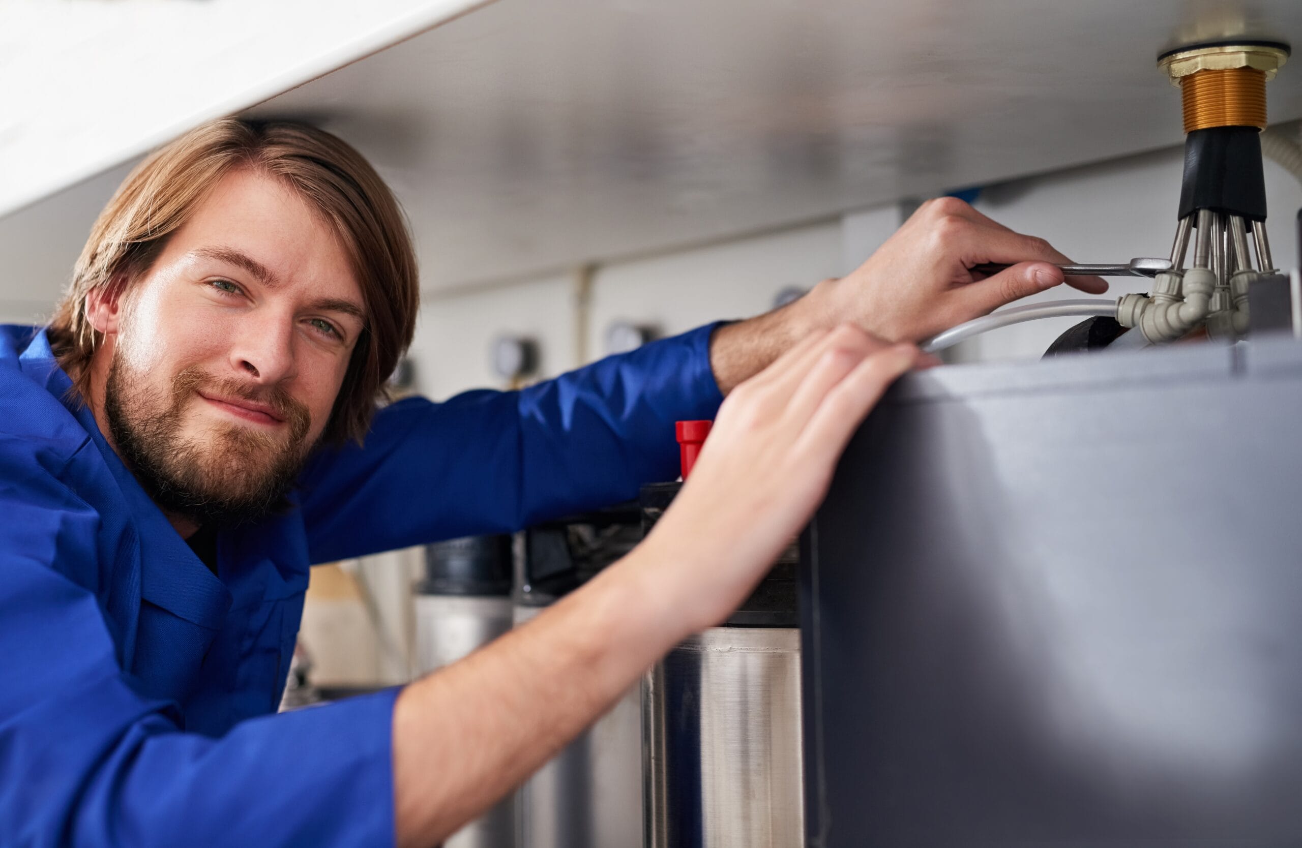 Technician servicing a residential water heater tank in West Covina